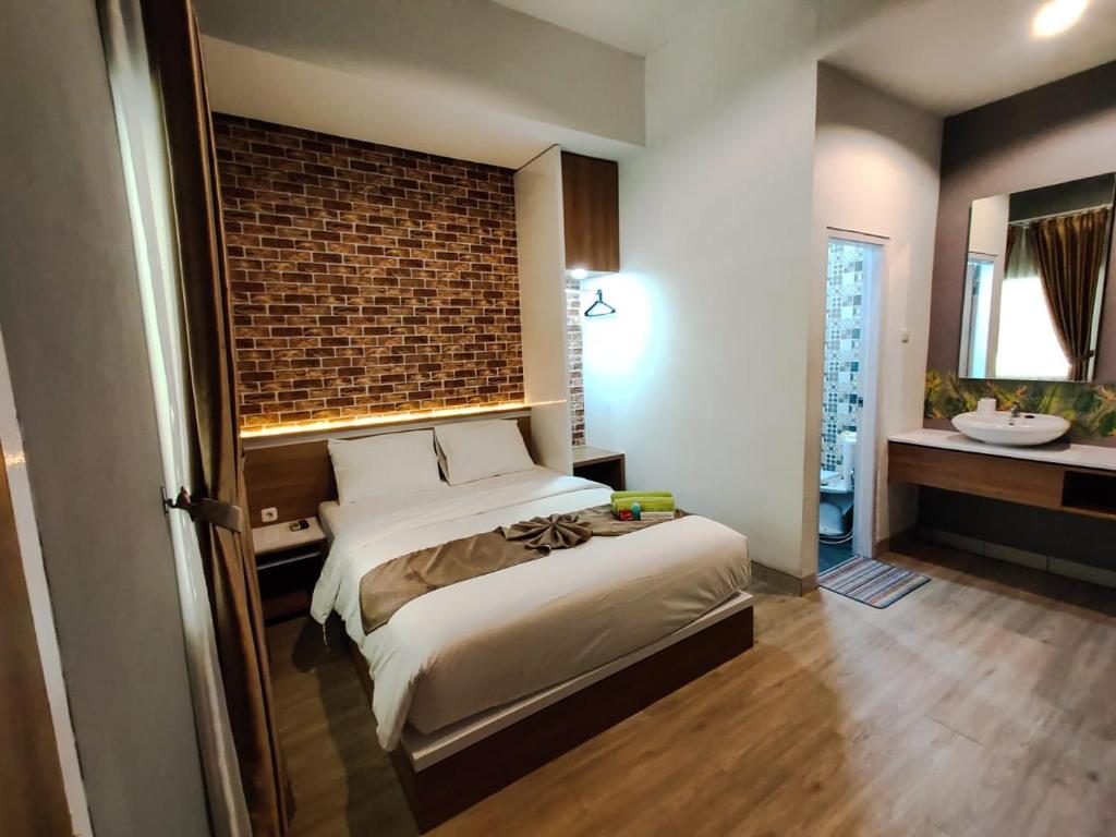 a bedroom with a bed and a bathroom with a sink at Caniga Hotel Yogyakarta in Gondowulung