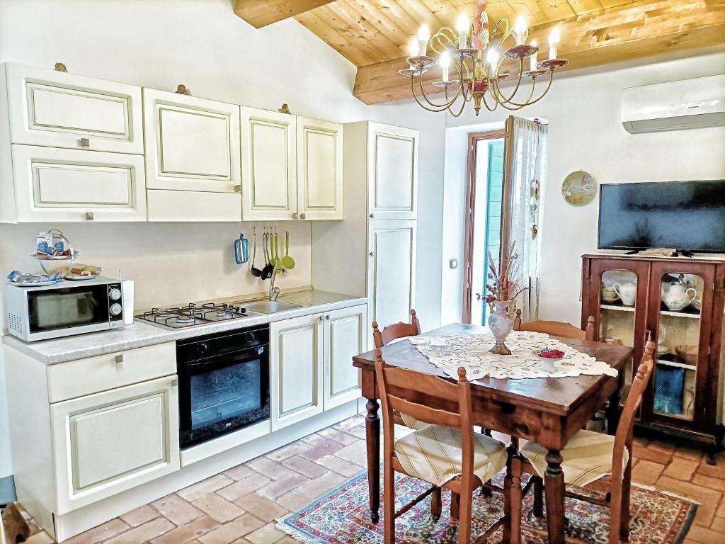 uma cozinha com armários brancos e uma mesa com cadeiras em Appartamento elegante em Morciano di Romagna