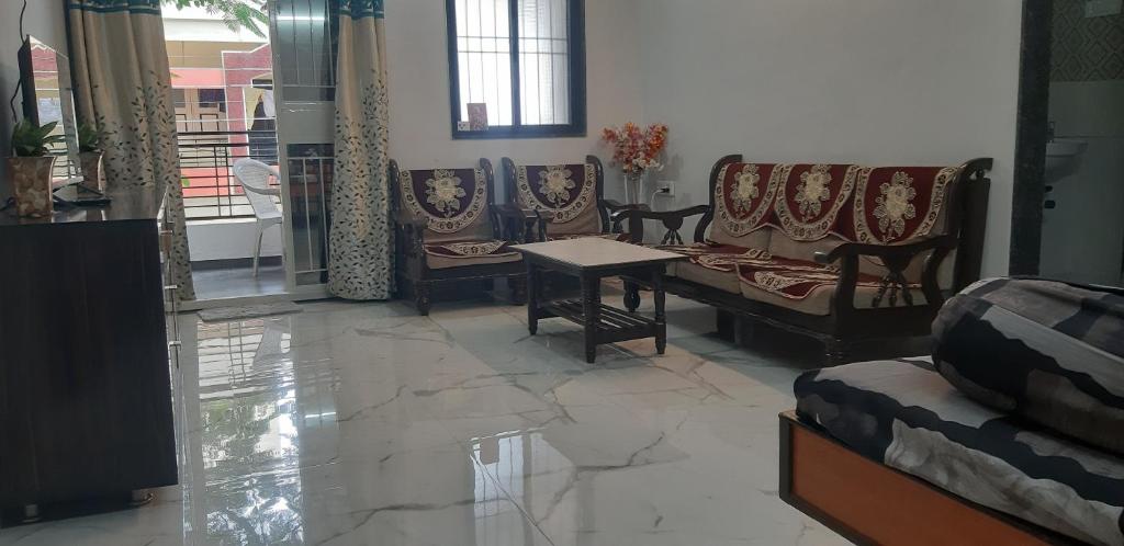 uma sala de estar com um sofá, cadeiras e uma mesa em Katke's HomeStay. em Sholapur