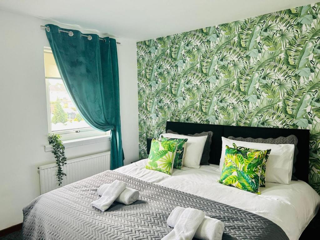 a bedroom with a large bed with a green wall at Elmbank Avenue House by Klass Living Uddingston in Uddingston