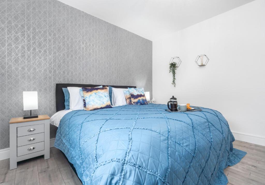 a bedroom with a bed with a blue comforter at Sanderson Apartment by Klass Living Uddingston in Uddingston