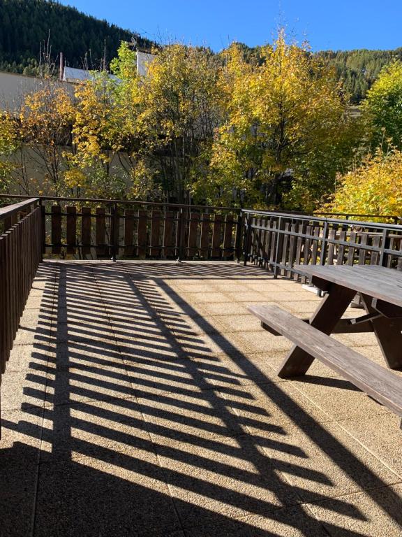 un tavolo da picnic in legno su un marciapiede accanto a una recinzione di Studio Avec belle terrasse proche des pistes a Uvernet