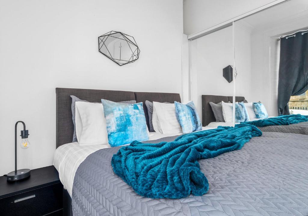 um quarto com uma cama com um cobertor azul em Garturk Apartment by Klass Living Coatbridge em Coatbridge