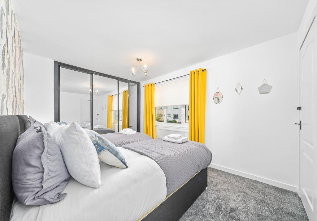 two beds in a bedroom with yellow curtains at Rothesay House by Klass Living Coatbridge in Coatbridge