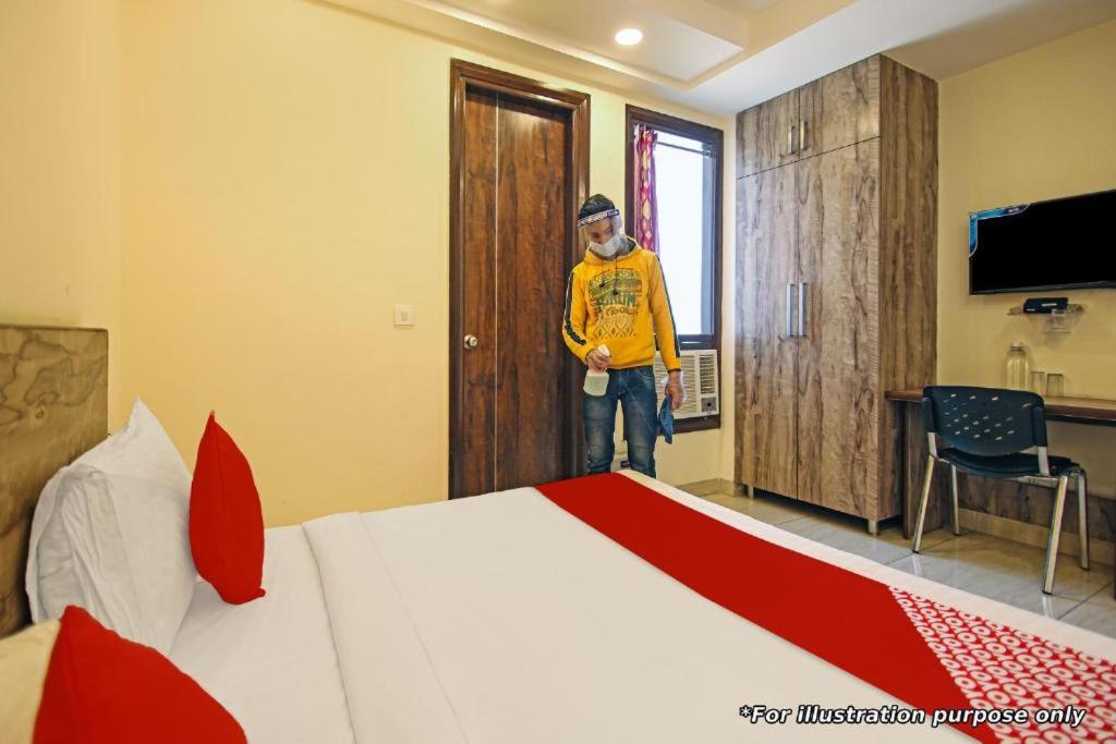 a man standing in a hotel room with a bed at The Urban Villa in Noida