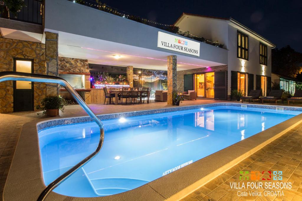 una piscina frente a un hotel por la noche en Villa Four Seasons, heated pool and 3 en-suite bathrooms en Velika Cista