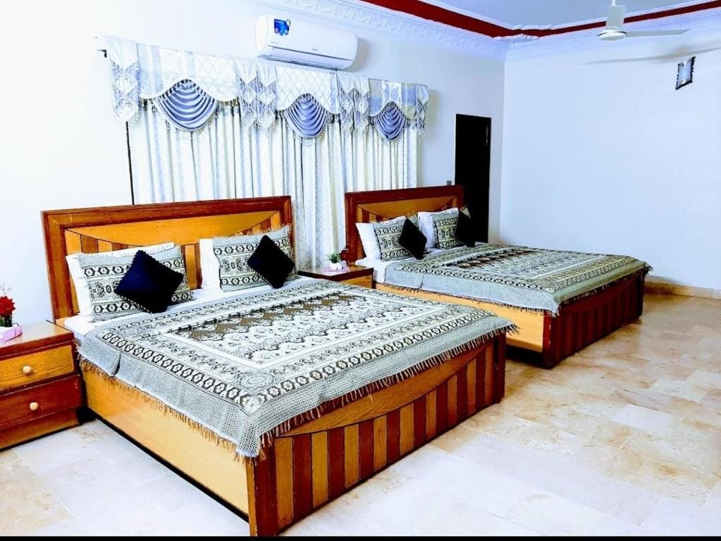 a bedroom with two beds and a window at Galaxy Inn in Karachi
