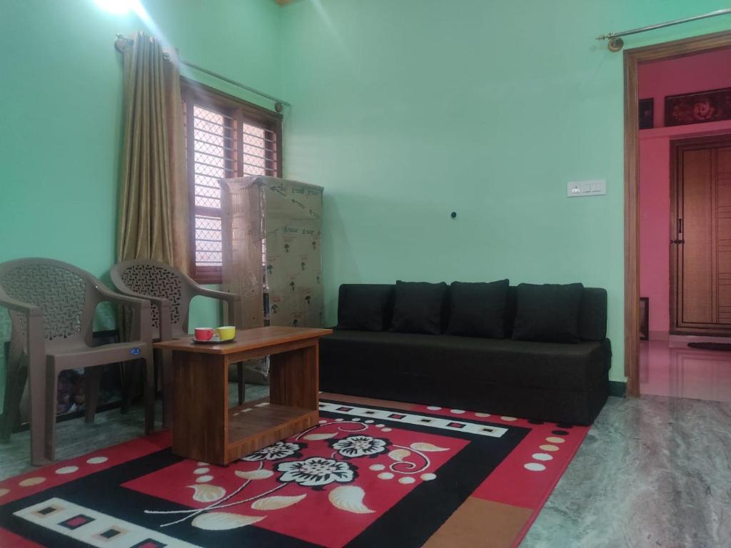 een woonkamer met een bank en een tafel bij Vrindavan - Cozy Stay in Mysore