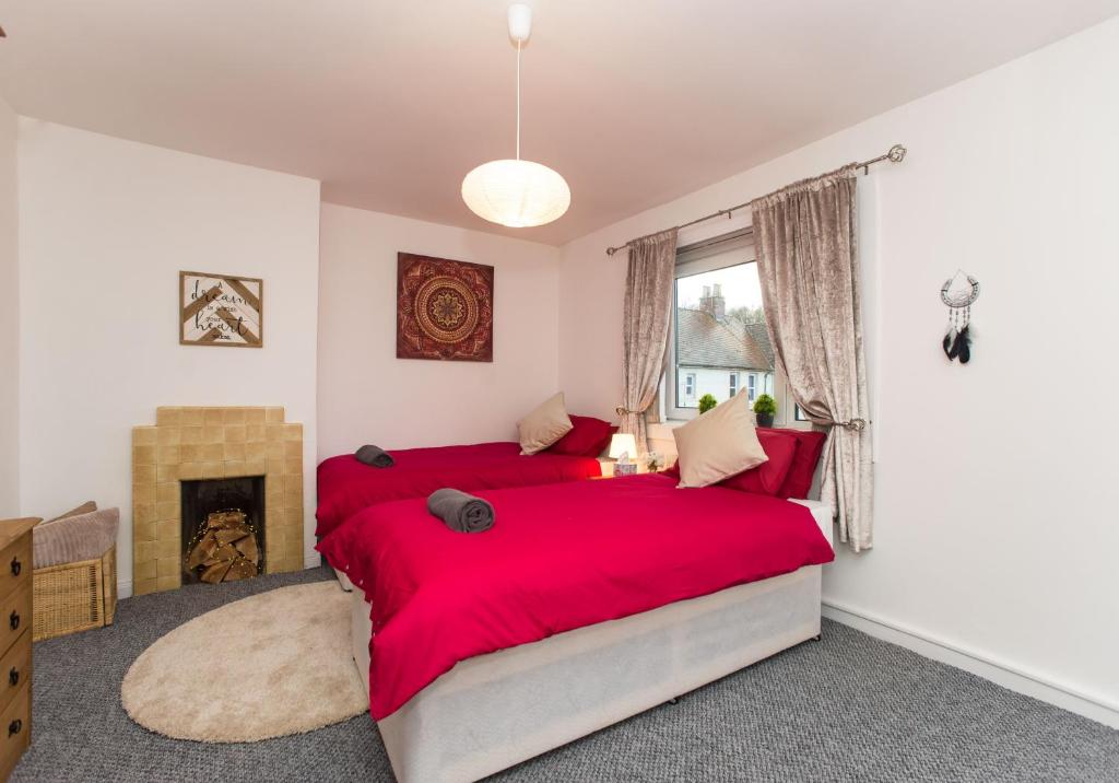 1 Schlafzimmer mit 2 roten Betten und einem Kamin in der Unterkunft Kenmar House by Klass Living Hamilton in Hamilton