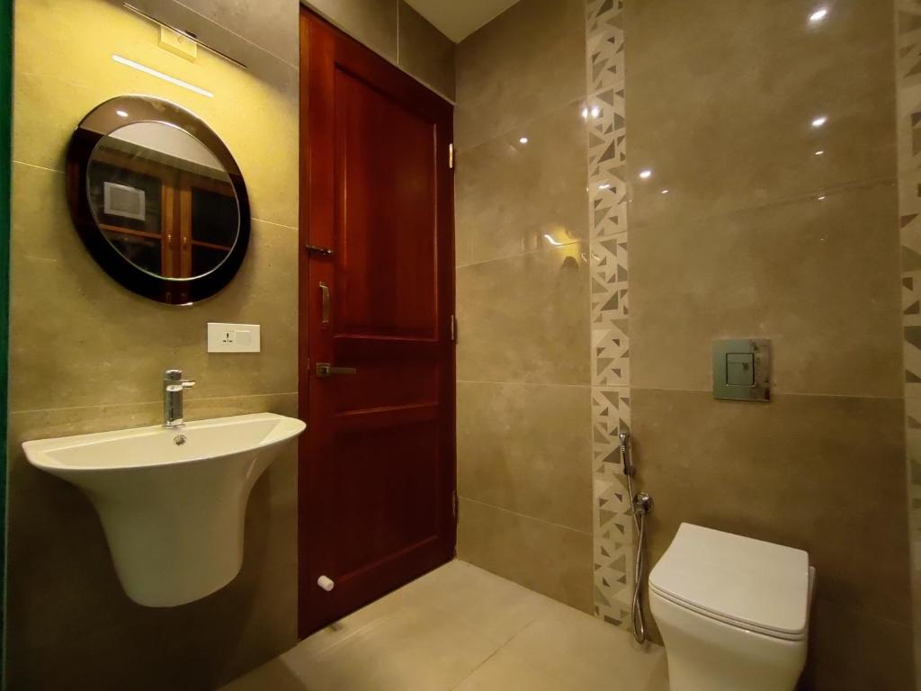 a bathroom with a sink and a toilet and a mirror at The Cana's Coorg in Ammatti