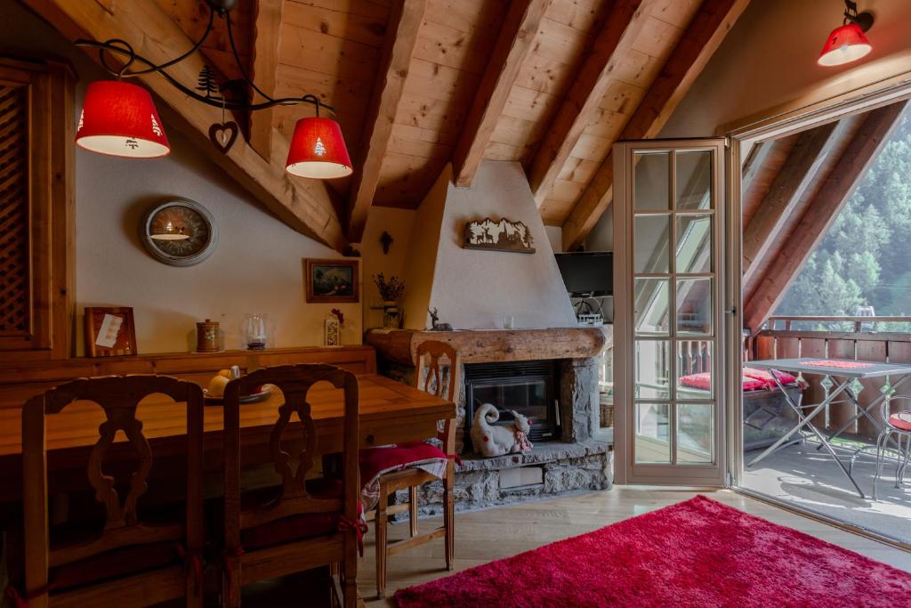 una sala da pranzo con camino, tavolo e sedie di Casa di Beatrice a Ponte di Legno