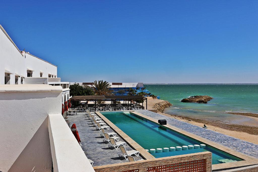 una piscina accanto all'oceano accanto a un edificio di Hôtel Calipau Riad Maison d'Hôtes a Dakhla