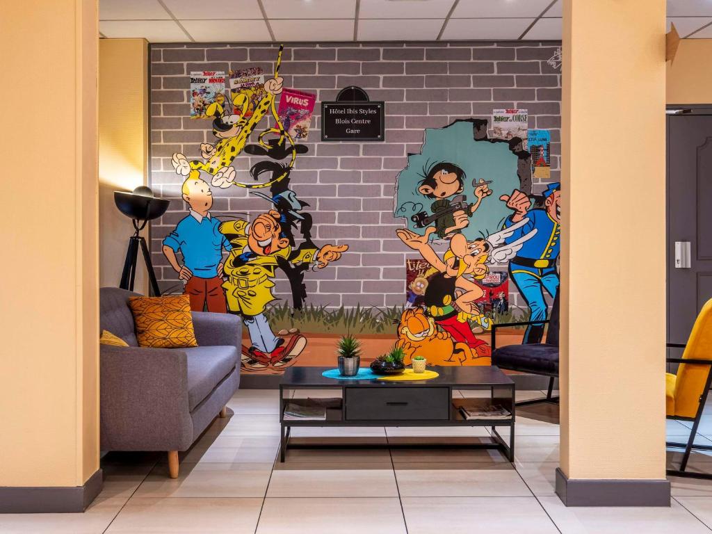 a living room with a wall mural of superheroes at ibis Styles Blois Centre Gare in Blois