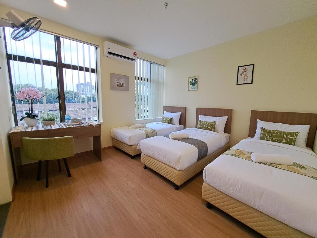 a hotel room with two beds and a desk and a window at SCC HOTEL PJ in Petaling Jaya