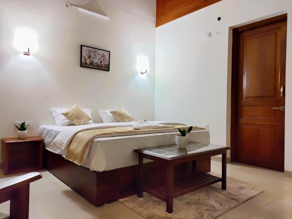 a bedroom with a bed with a table and a door at The Cana's Coorg in Ammatti