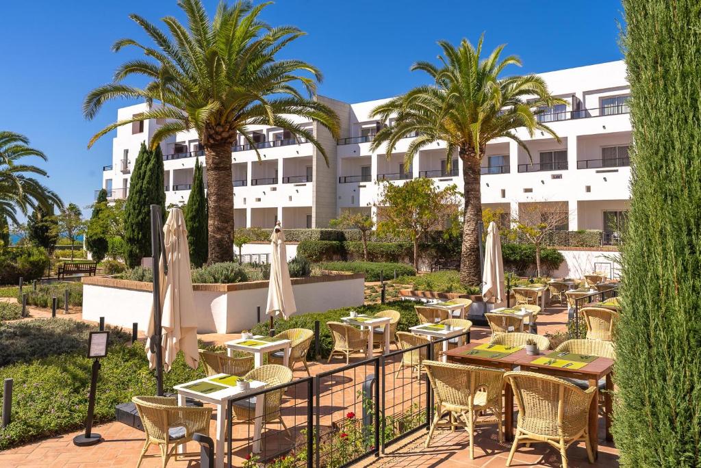 a restaurant with tables and umbrellas in front of a building at Hotel Fuerte Conil-Resort in Conil de la Frontera