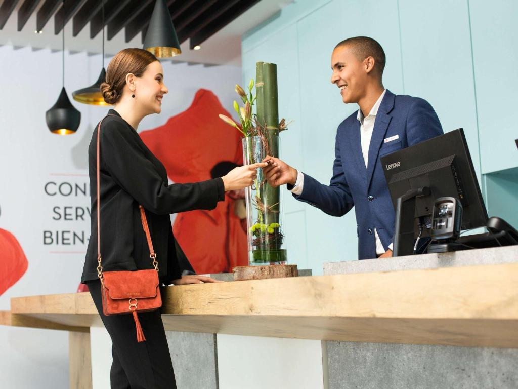 a man and a woman shaking hands at a counter at Ibis Casa Voyageurs in Casablanca