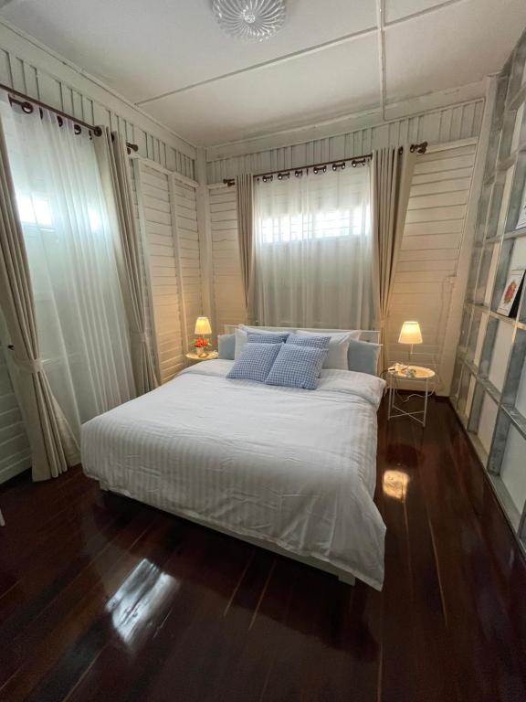 a bedroom with a large white bed with blue pillows at บ้านแสนรัก Casa Dolce Casa, Prakhon Chai in Prakhon Chai