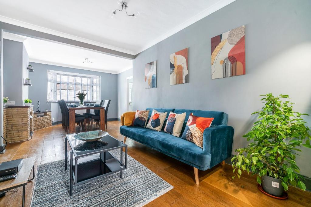 ein Wohnzimmer mit einem blauen Sofa und einem Tisch in der Unterkunft Stunning 3BR House w Garden & Parking in Richmond in Kew Gardens