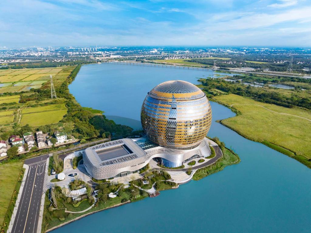 une vue aérienne d'un bâtiment à côté d'une masse d'eau dans l'établissement Hilton Huzhou Nanxun, à Huzhou
