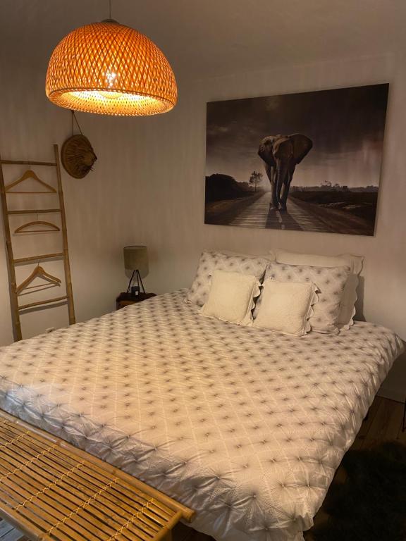 1 cama en un dormitorio con una pintura en la pared en La Suite Cosy - Votre Pause Arborée en La Bruyère