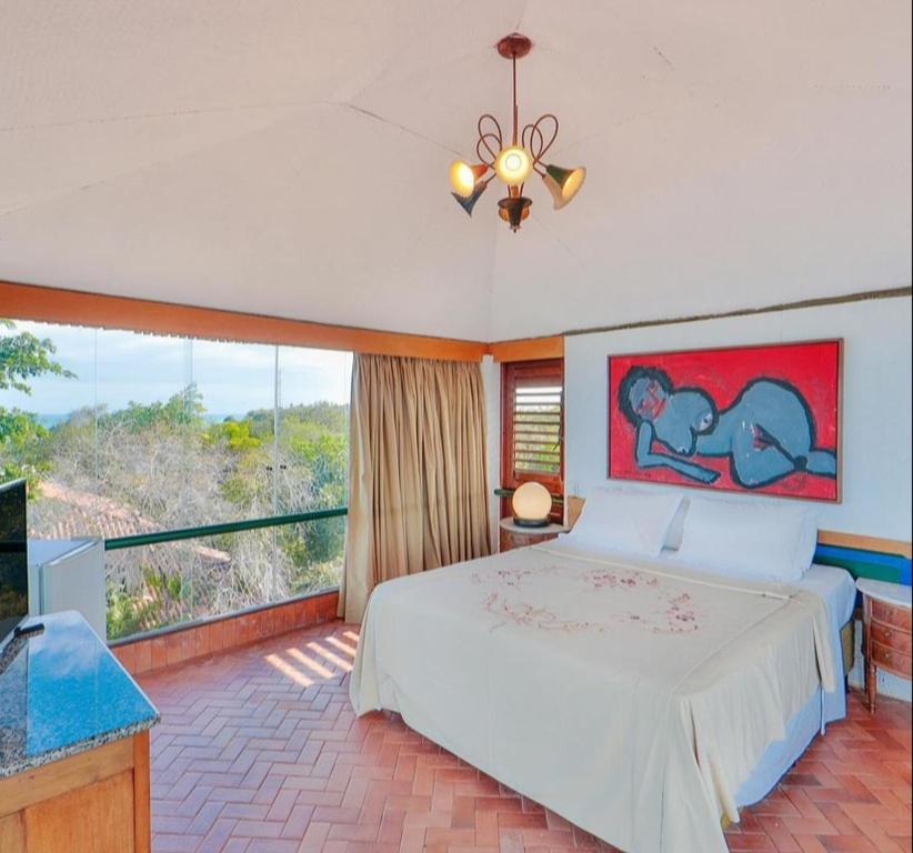 a bedroom with a large bed and a large window at Pousada do Alto in Japaratinga