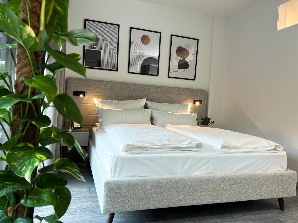 ein Schlafzimmer mit einem Bett mit weißer Bettwäsche und einer Pflanze in der Unterkunft ARUS Hotels in Hamburg