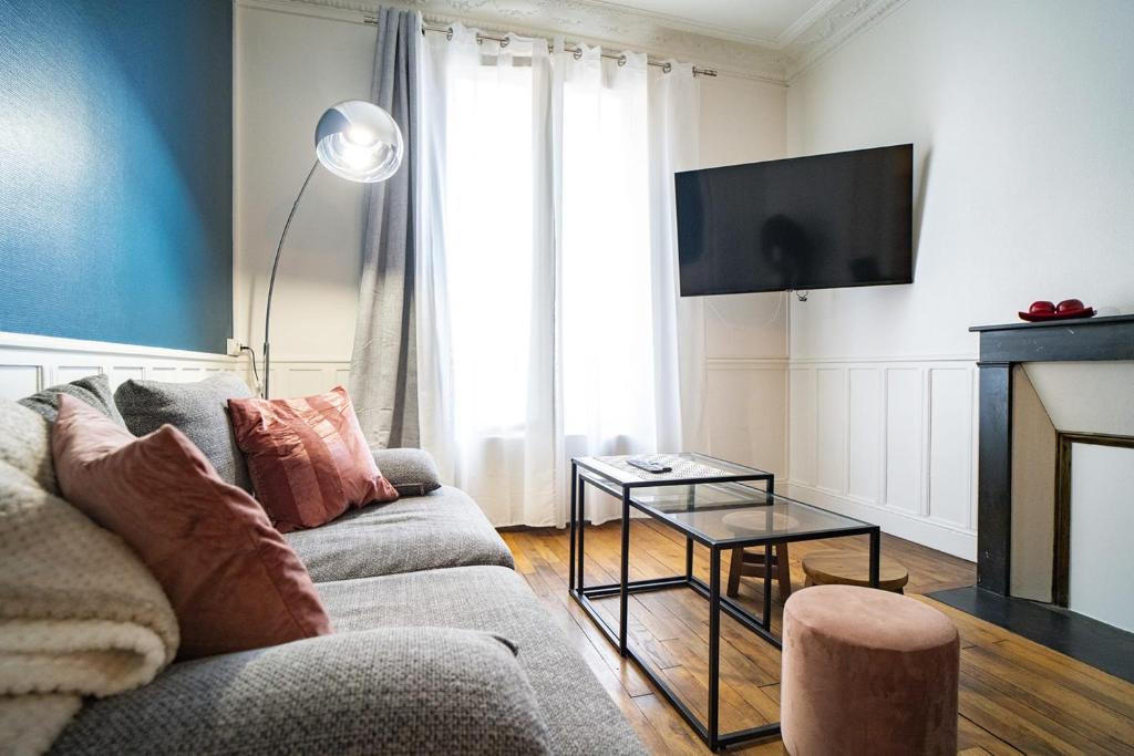 a living room with a couch and a tv at Cozy love cocoon in Boulogne-Billancourt's heart in Boulogne-Billancourt
