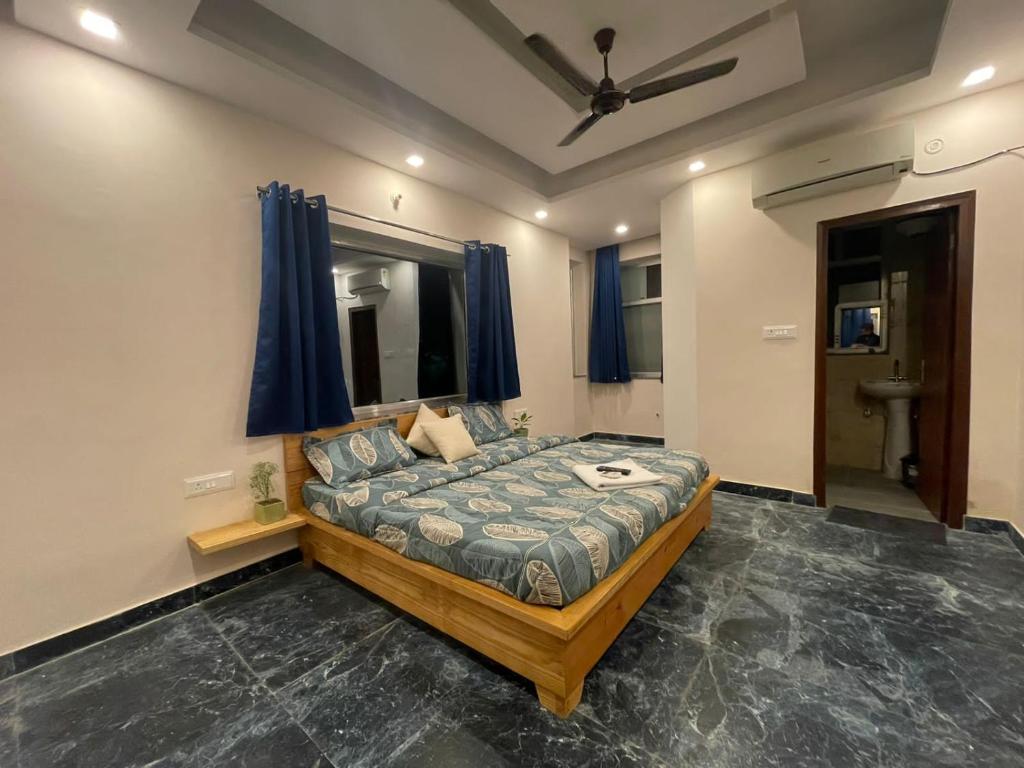 a bedroom with a bed and a window with blue curtains at Kalakriti Homestay in Rishīkesh