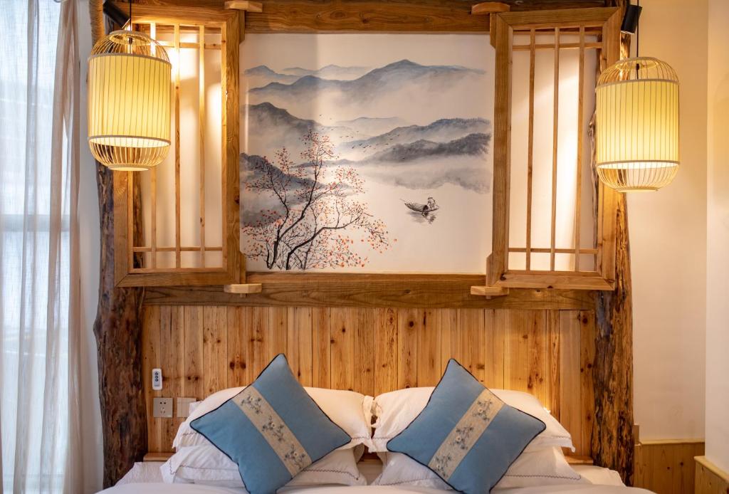 a bedroom with a bed with two lamps and a painting on the wall at Zhangjiajie Yueting Eco Inn in Zhangjiajie