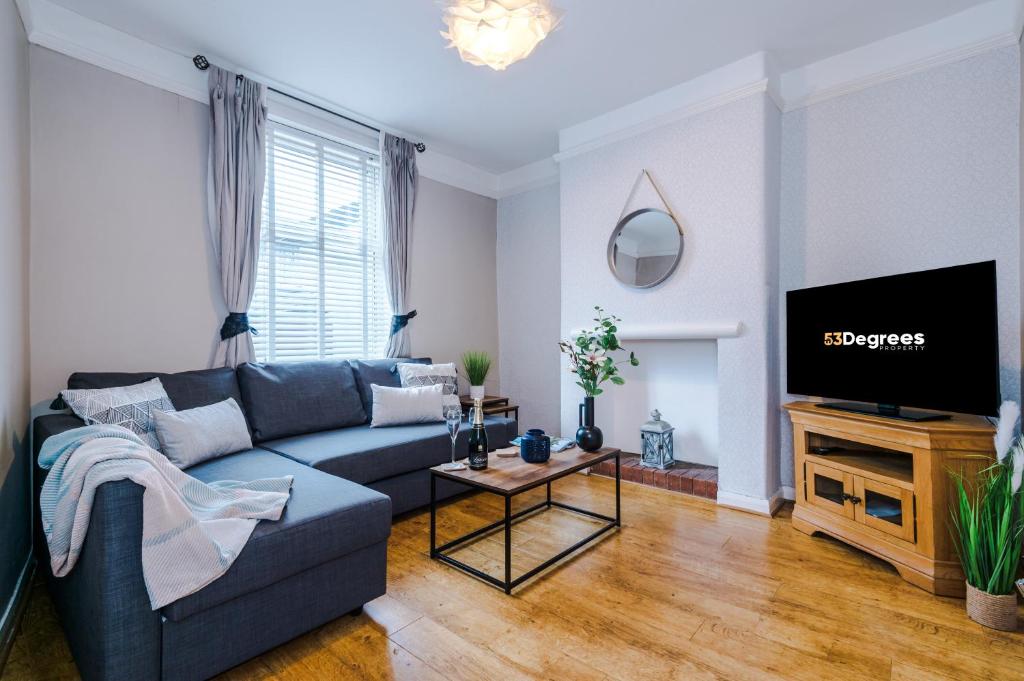 ein Wohnzimmer mit einem blauen Sofa und einem TV in der Unterkunft NEW! Spacious 2-bed home in Chester by 53 Degrees Property, Ideal for Long Stays, Great location - Sleeps 6 in Chester