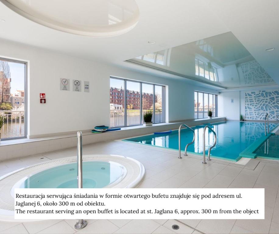 a large swimming pool in a building with a large window at Flatbook - City Center SPA Apartments Waterlane Island in Gdańsk