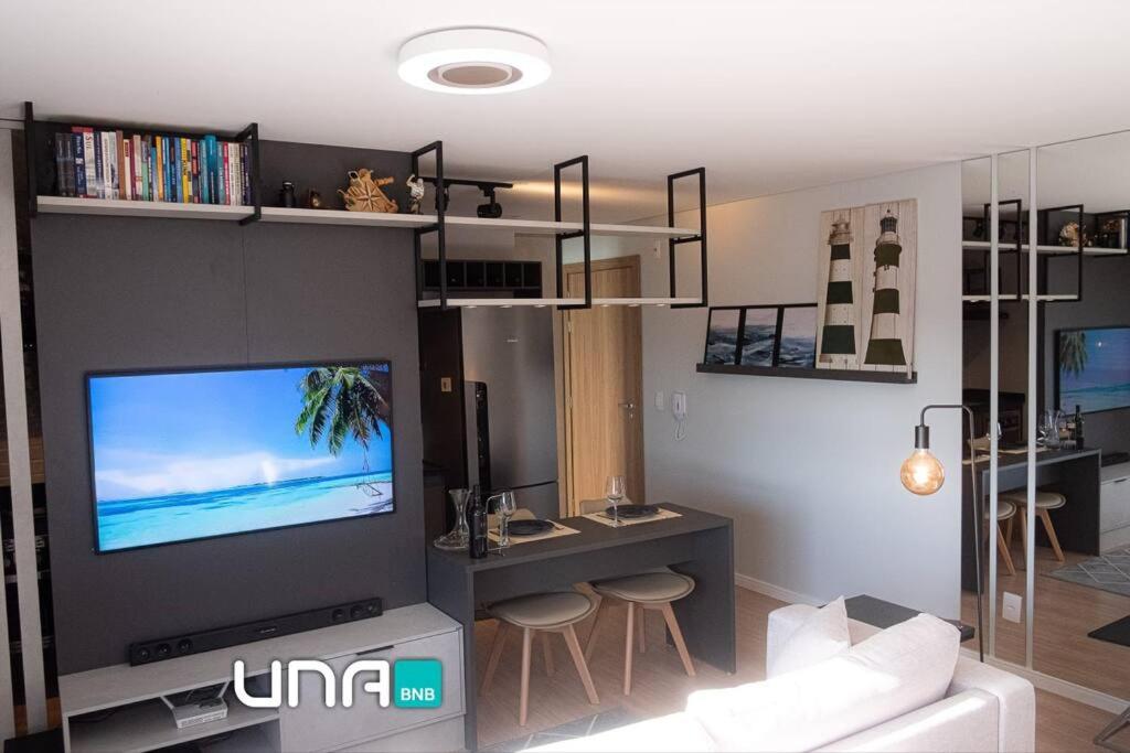 ein Wohnzimmer mit einem Flachbild-TV an der Wand in der Unterkunft Studio perfeito no Parque Una com vaga de garagem in Pelotas