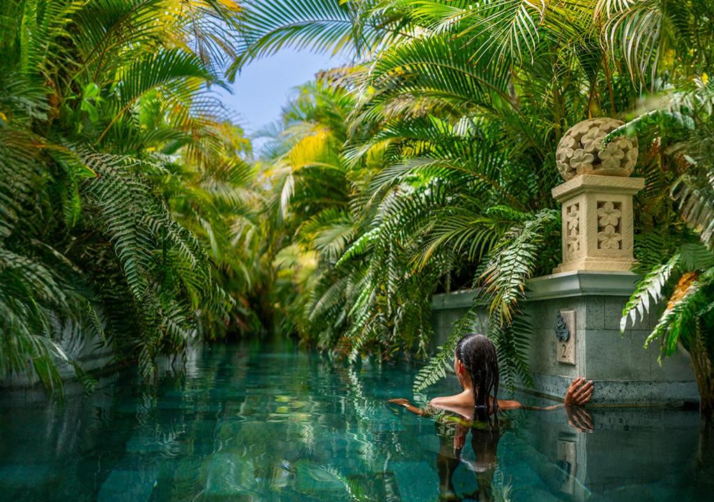 una mujer sentada en un charco de agua con palmeras en Royal River, Luxury Hotel - Adults Only en Adeje