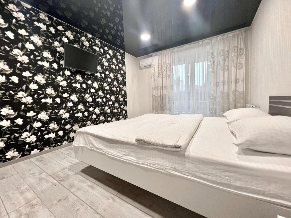 - une chambre avec un lit et une télévision murale dans l'établissement ApartPoltava 2 ОКРЕМІ кімнати, новобудова, ДВА великих ліжка ЦЕНТР, КОРПУСНИЙ САД, à Poltava