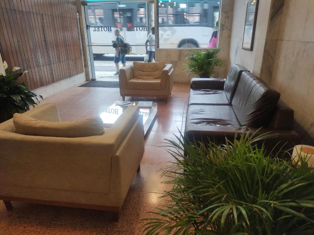 un soggiorno con divani, sedie e piante di Mônaco Hotel a Juiz de Fora