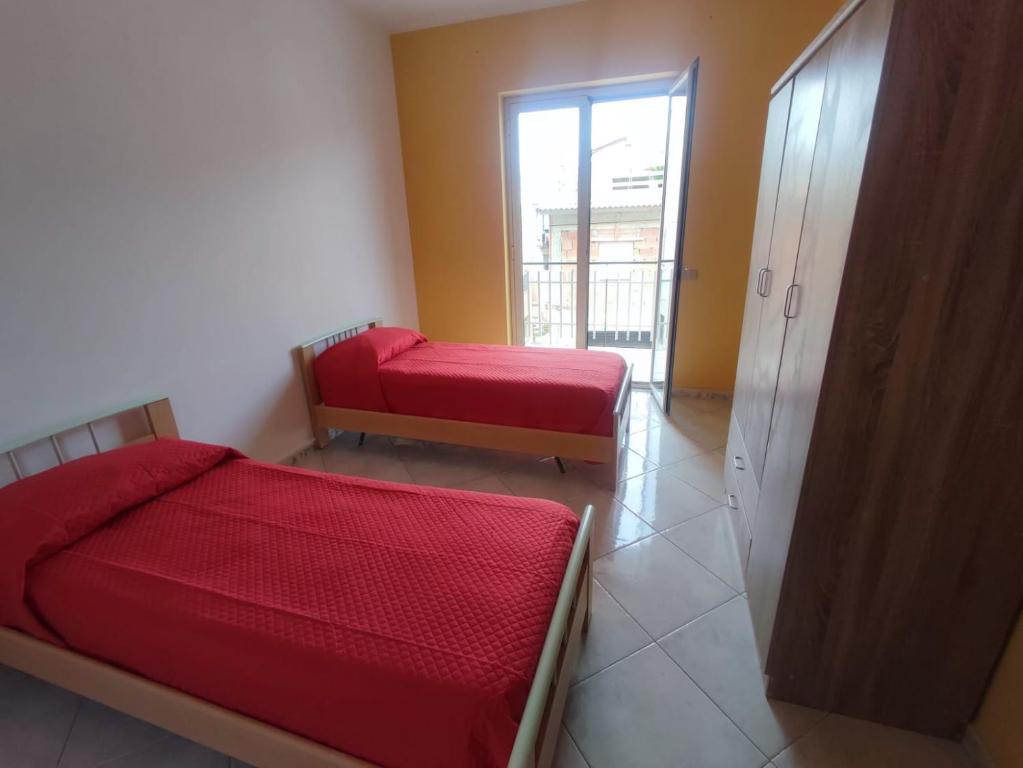 - une chambre avec 2 lits rouges et une fenêtre dans l'établissement Casa Vacanze Il Tramonto Spadafora, à Spadafora