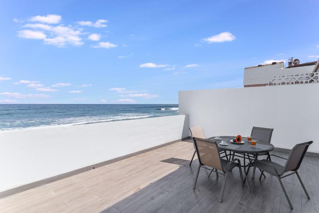 eine Terrasse mit einem Tisch und Stühlen am Strand in der Unterkunft Home2Book Marly Ocean View San Andrés Beach in Arucas