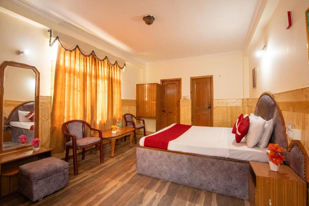 a hotel room with a bed and a table and chairs at Octave Hillans Manali in Manāli