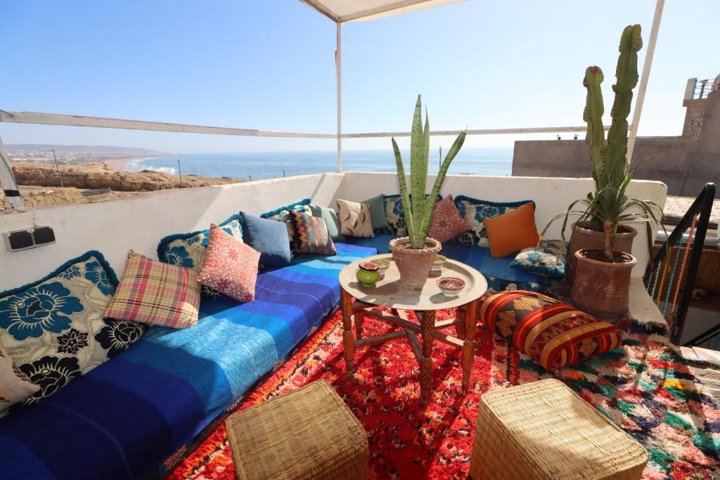 un sofá con almohadas y una mesa en el balcón en Welle Surf Morocco, en Taghazout