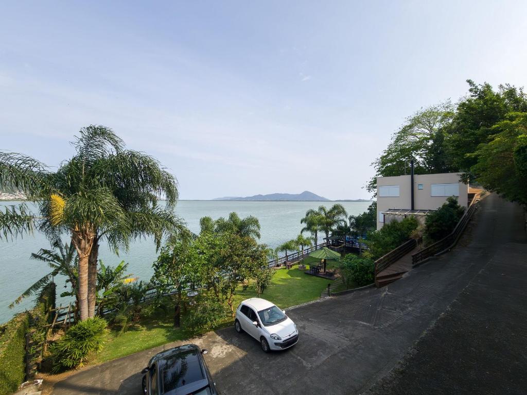 a white car parked in a parking lot next to the water at Casa à beira-mar com piscina Floripa-SC RJD156 in Florianópolis