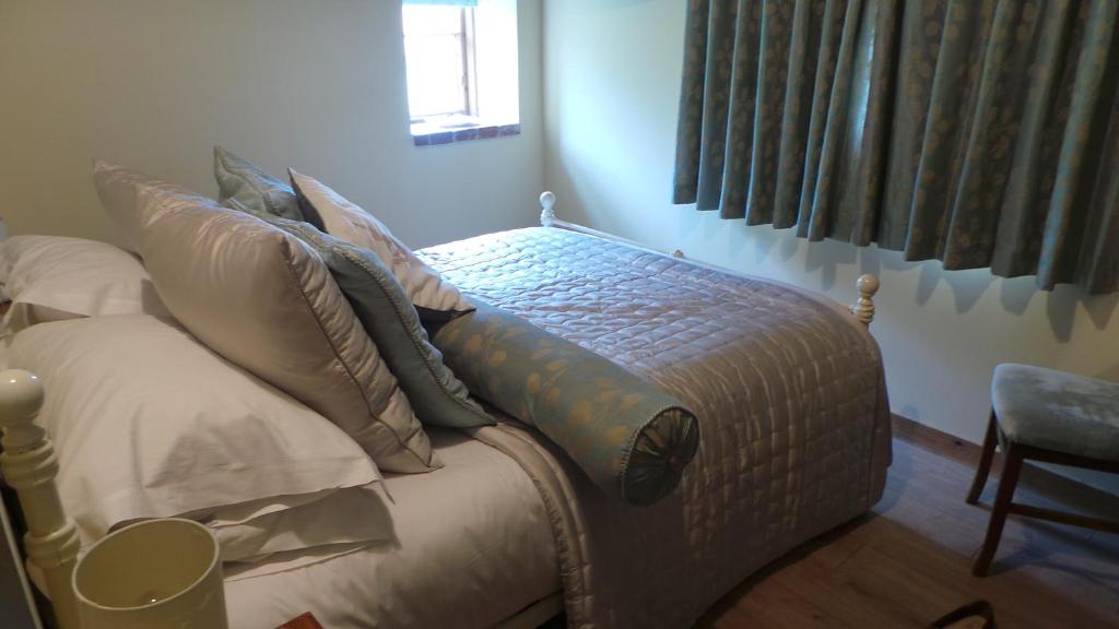 una cama con almohadas en una habitación en Pond Cottage, en Egerton