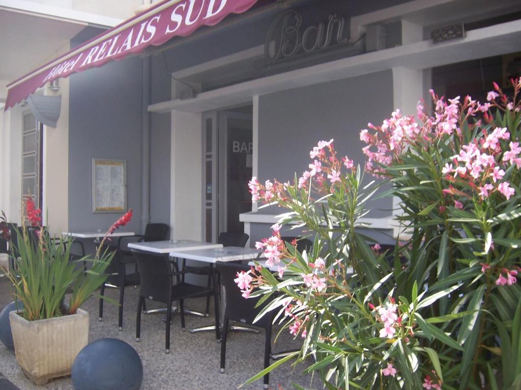 un restaurante con mesas, sillas y flores rosas en Hotel Relais Sud, en Valence