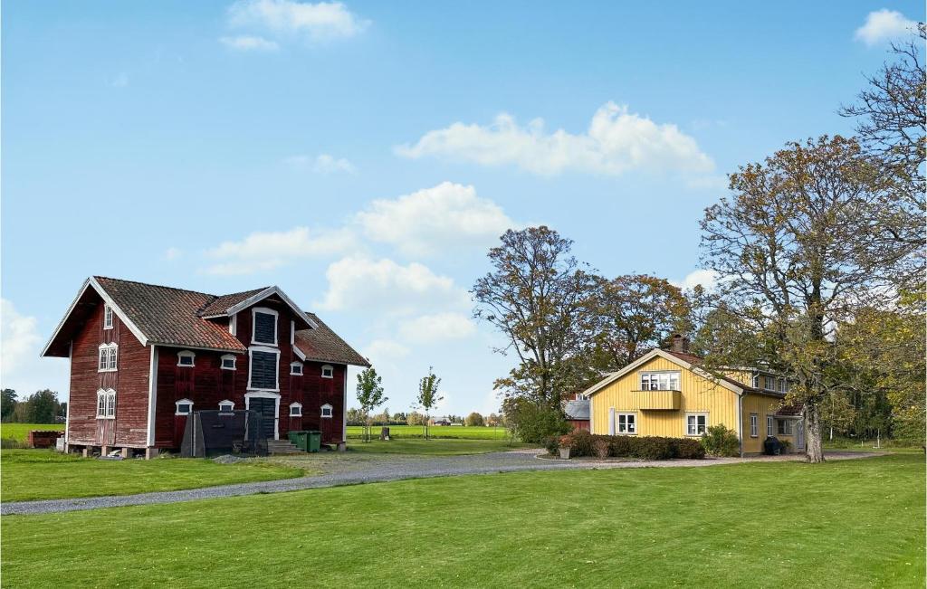 um celeiro vermelho e uma casa amarela num campo em 4 Bedroom Cozy Home In Jnkping em Jönköping
