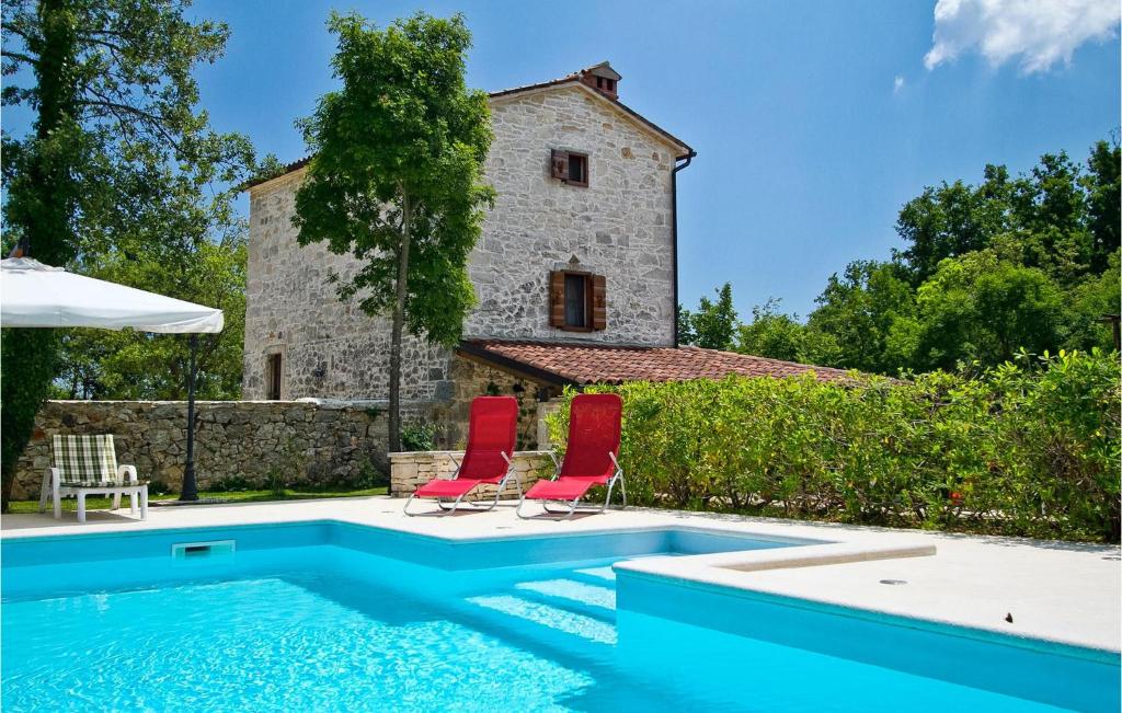 a pool with two red chairs next to a building at Villa Stancija Bursic in Pula