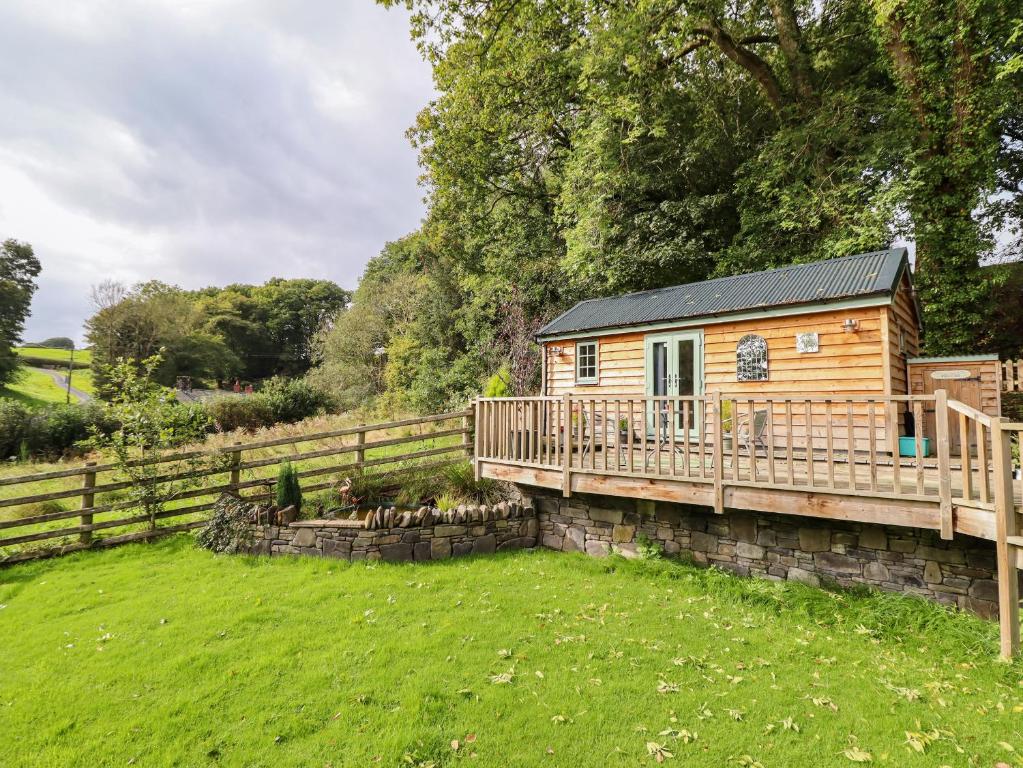 a wooden cabin in a yard with a fence at Chateau Petit in Caersws