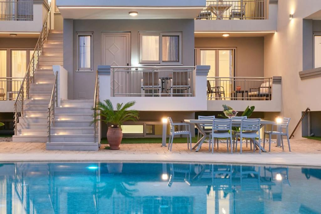 una piscina con sillas, una mesa y una casa en Modern Family apartment Ewa with pool, dining area on Crete coast, en Stavromenos
