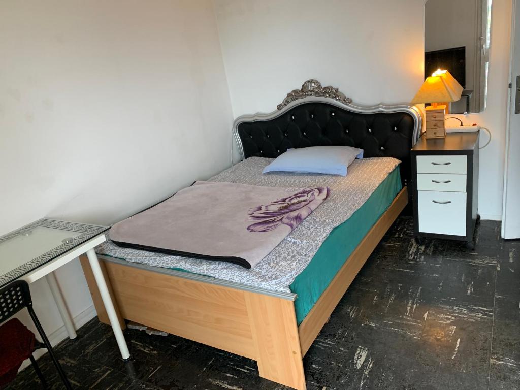 ein kleines Bett mit einem Holzrahmen und einem Schreibtisch in der Unterkunft Une chambre single avec accès direct Aéroport d'Orly T4 in Orly