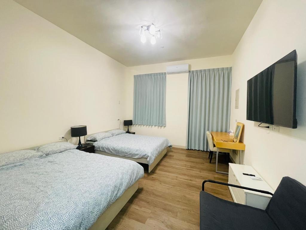 um quarto de hotel com duas camas e uma televisão de ecrã plano em Hongqiao Inn 桃園市民宿編號136號 em Longtan