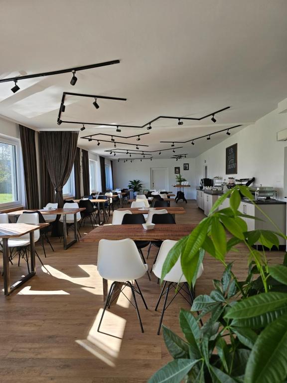 uma grande sala com mesas, cadeiras e plantas em Hotel Fuchs & Hase SELF CHECK IN em Rosegg
